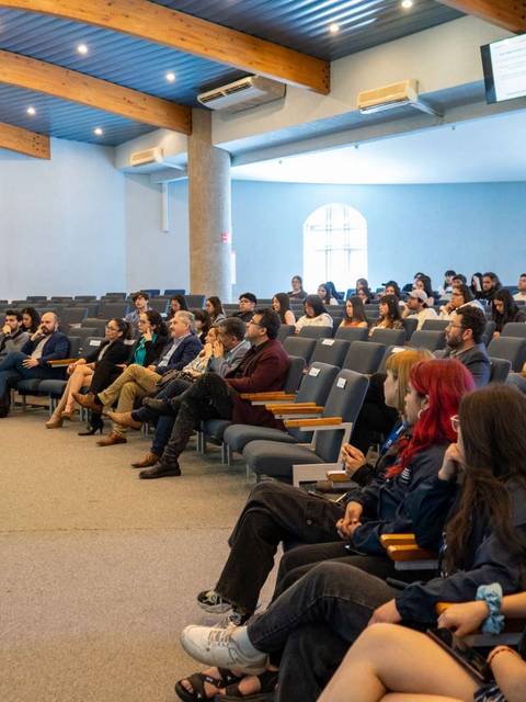 Una conferencia con un ponente hablando frente a un gran público en un auditorio.