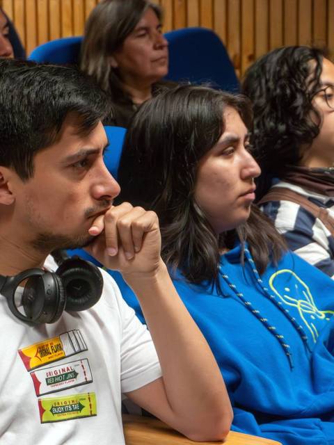 Un grupo de jóvenes atentos durante una presentación en un auditorio.