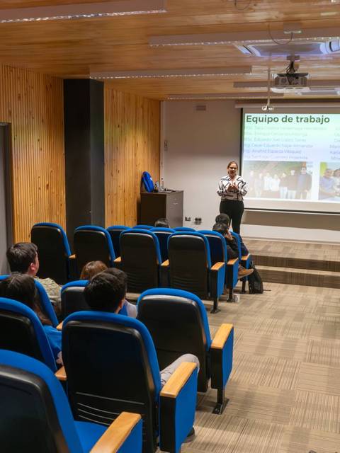 Una presentación en un aula con varias personas escuchando a un expositor.