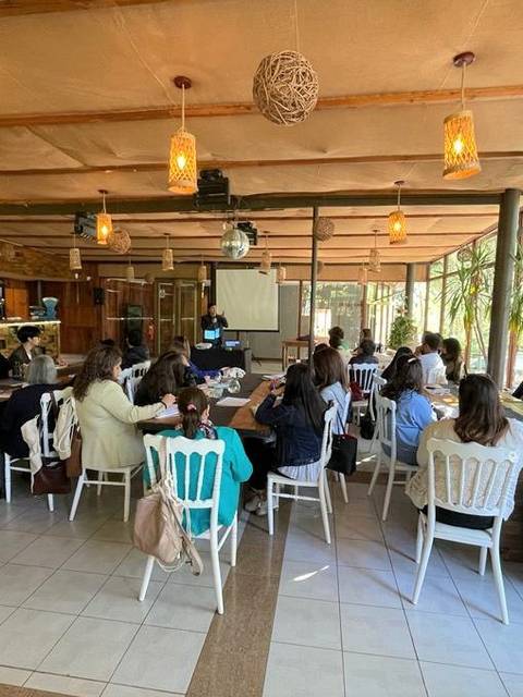 Un grupo de personas sentadas en un salón durante una presentación.