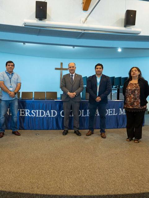 Un grupo de personas posando frente a un fondo con el logotipo de la Universidad Católica del Maule.