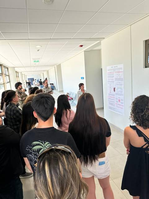 Un grupo de personas observa un cartel informativo en un pasillo amplio y luminoso.