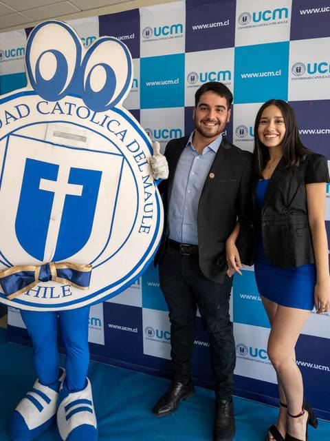 Un grupo de personas sonríen junto a una mascota en un evento de la Universidad Católica del Maule en Chile.