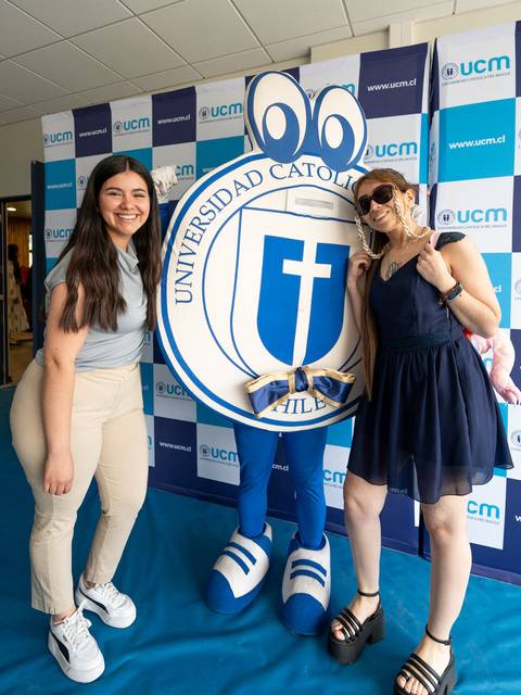 Dos jóvenes posan junto a una mascota representativa de la Universidad Católica.