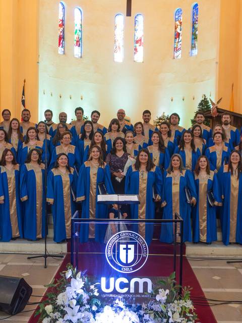 Un grupo de personas vestidas con togas azules se presenta en un escenario durante un evento en una iglesia.
