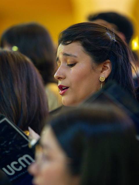 Un grupo de personas canta en un coro, mostrando expresiones de concentración y emoción.