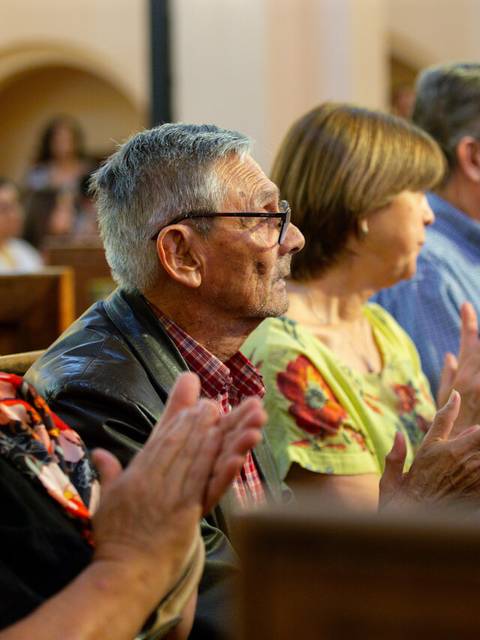 Un grupo de personas aplaudiendo en un evento dentro de un recinto cerrado.