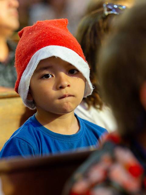 Un niño con un sombrero navideño observa atentamente en un ambiente festivo.