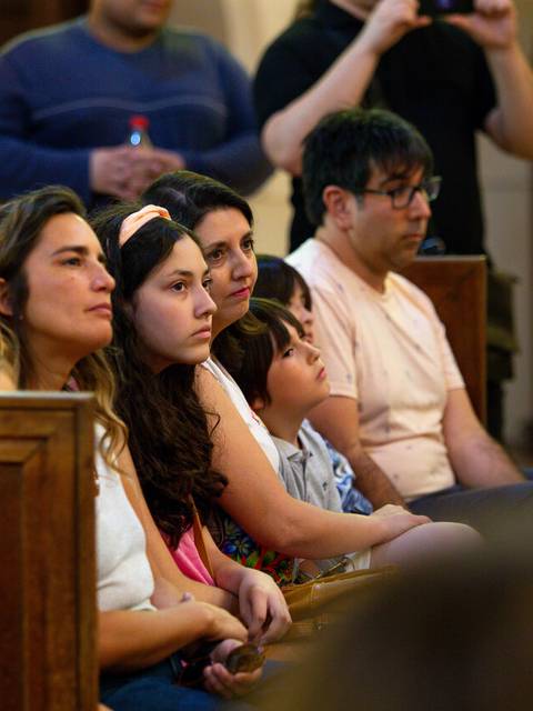 Un grupo de personas sentadas en un salón, aparentando estar atentas a un evento.