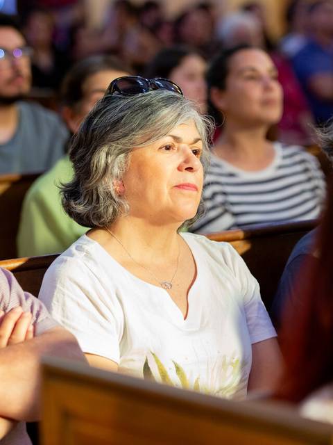 Una multitud de personas sentadas en un evento, mostrando atención y reflexión.