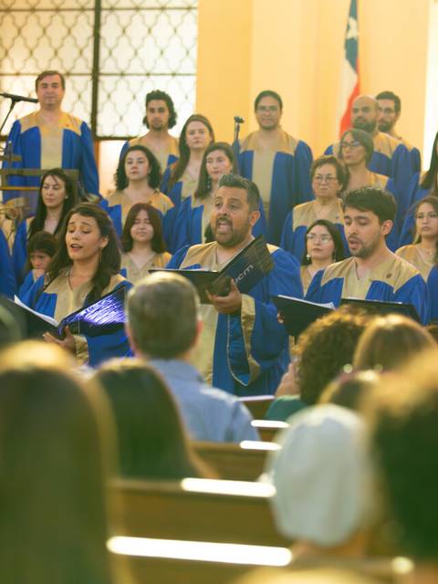 Un coro de personas cantando en una iglesia, con miembros vestidos con túnicas azules y doradas.