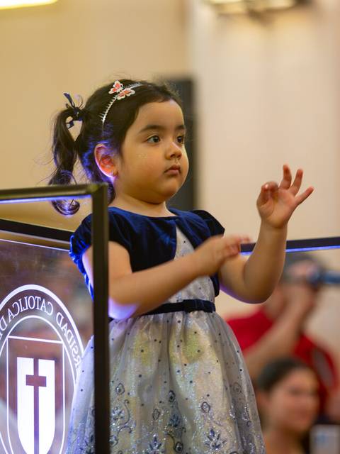 Una niña pequeña está de pie frente a un panel, mientras observa atentamente a su alrededor en un ambiente familiar.
