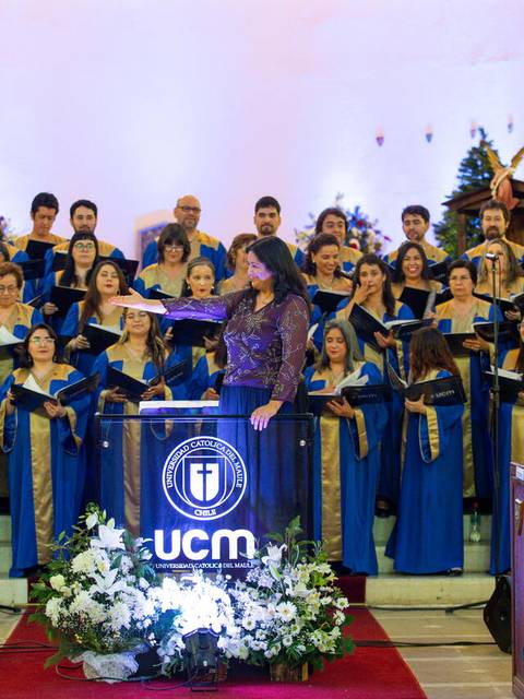 Un coro de personas vestidas con túnicas azules y doradas se presenta en un escenario ante una audiencia.