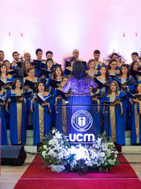 Un coro de personas vestidas de azul se presenta en un escenario iluminado.