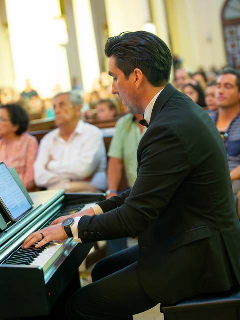 Un pianista vestido de traje toca en un concierto frente a un público atento.