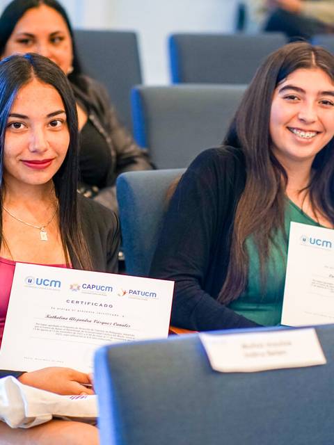 Dos jóvenes sonrientes sosteniendo certificados en un evento.