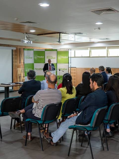 Una sala de conferencias con un orador en un podio y un público sentado frente a él.