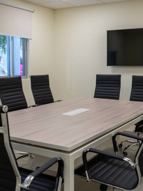 Sala de reuniones equipada con una mesa grande y sillas negras.