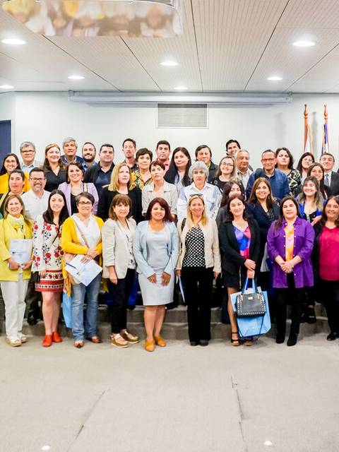 Un grupo numeroso de personas posando juntas en un auditorio.