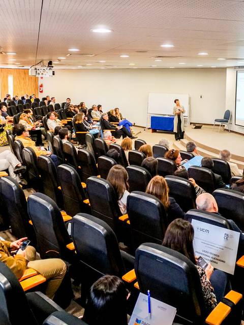 Una sala de conferencias con un gran número de asistentes escuchando a un presentador.