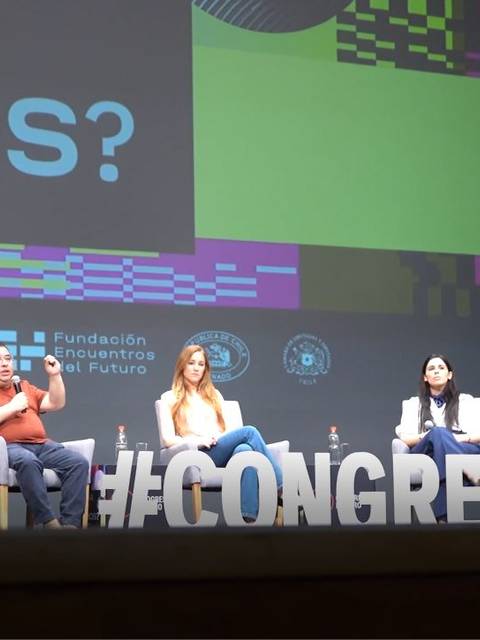 Un panel de discusión en un congreso con cinco participantes en el escenario.