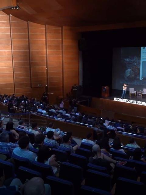 Una sala de conferencias llena de audiencia atenta durante una presentación.