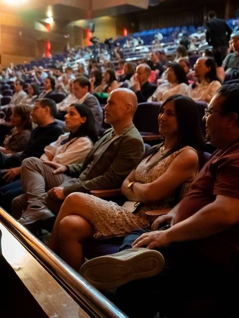 Un público diverso sentado en un auditorio durante un evento.
