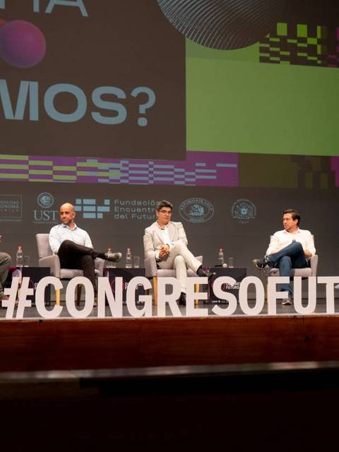 Un grupo de personas discutiendo en una conferencia en un auditorio.
