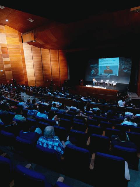 Una audiencia asistiendo a una presentación en un auditorio moderno.