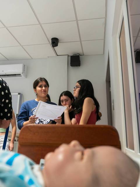 Un grupo de tres mujeres están conversando en una habitación con un muñeco en primer plano.