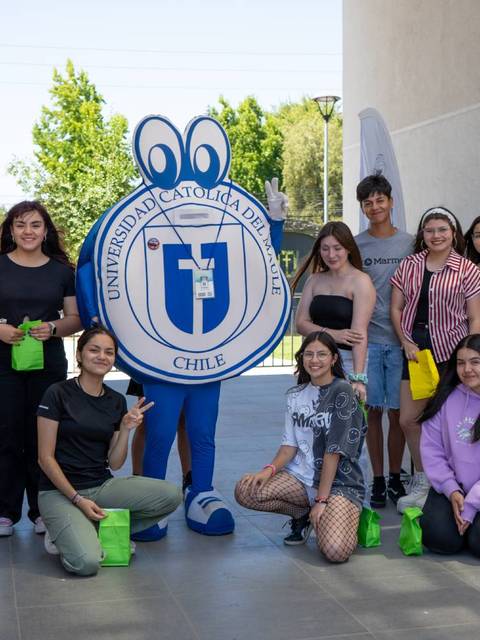 Grupo de estudiantes con un personaje del logo de la universidad en un ambiente exterior.