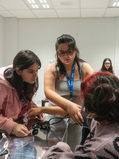 Un grupo de estudiantes está aprendiendo a tomar la presión arterial en un aula.