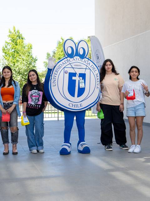 Un grupo de personas posando con una mascota cartoon y banderas en un espacio exterior.