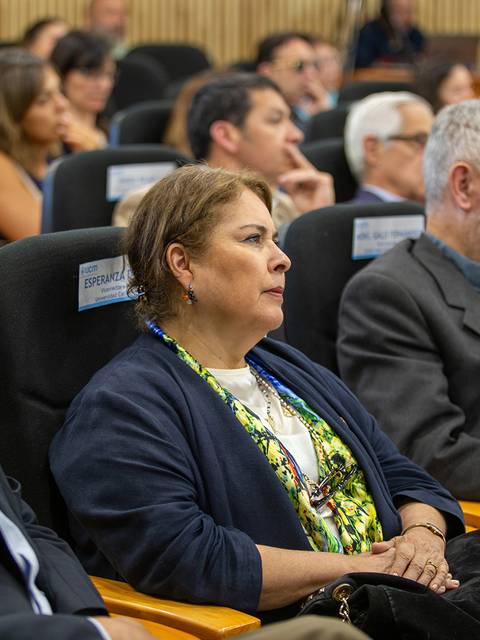 Un grupo de personas atentas en una conferencia, sentadas en asientos del auditorio.