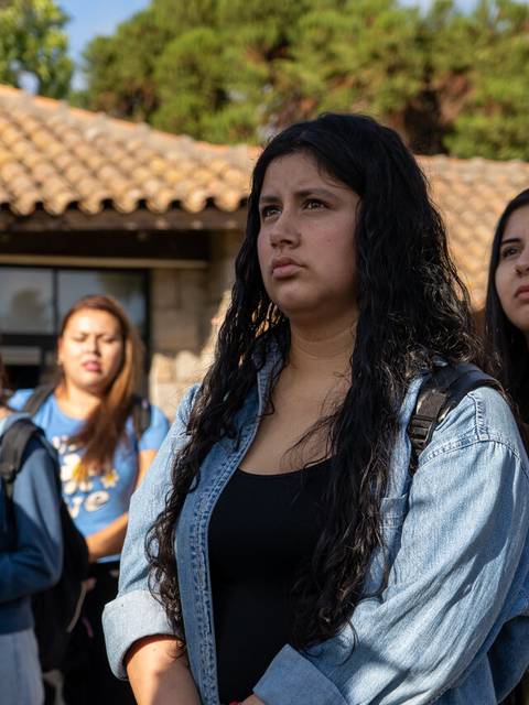 Un grupo de jóvenes observa atentamente una actividad al aire libre.
