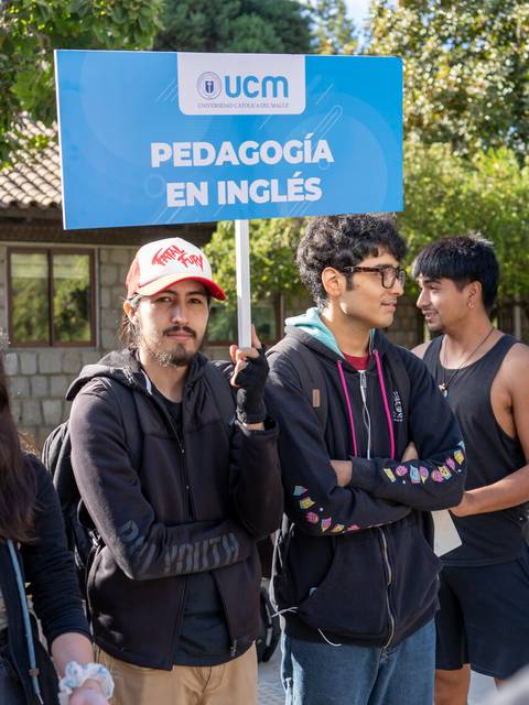 Un grupo de jóvenes sostiene un cartel que promueve un programa de pedagogía en inglés.