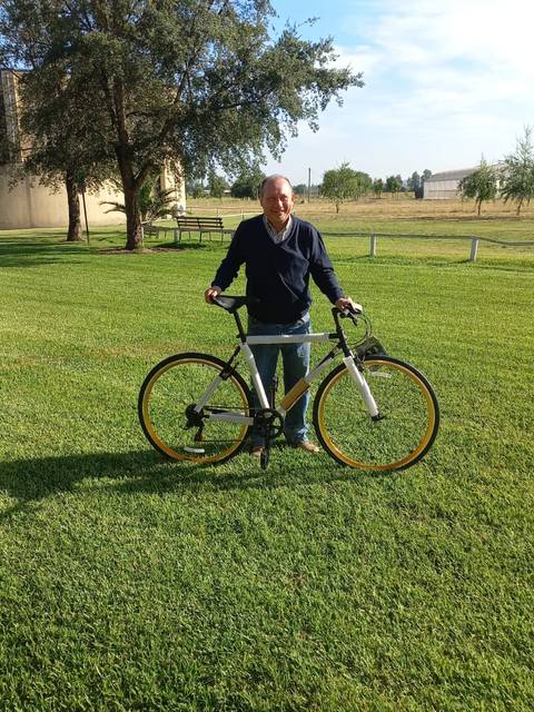 Un hombre está de pie sosteniendo una bicicleta en un campo de césped verde.