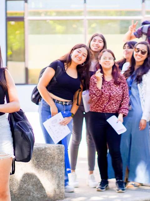 Un grupo de jóvenes sonrientes posando para una foto al aire libre.