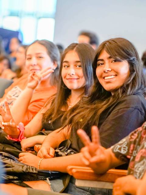 Un grupo de jóvenes sonrientes se encuentra en un auditorio.