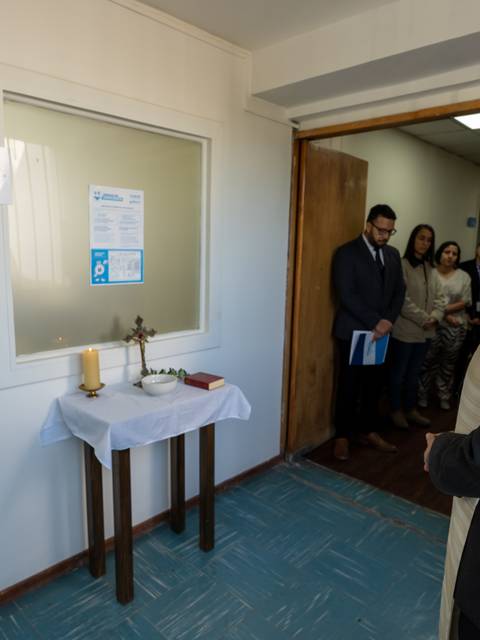 Una ceremonia de inauguración en un edificio con personas observando y un altar preparado.