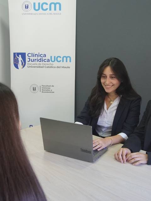 Dos mujeres están sentadas en una mesa frente a una laptop en un entorno de oficina.