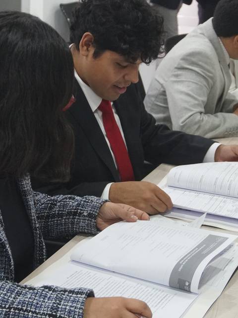 Un grupo de jóvenes revisa documentos en una mesa de trabajo.