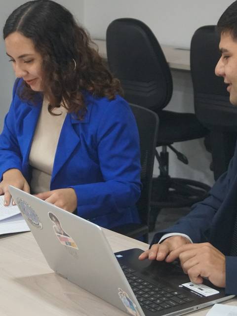 Dos personas colaborando en una reunión de trabajo en una oficina.