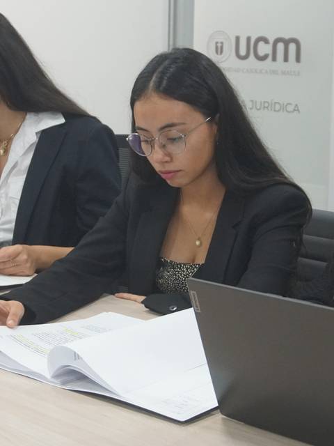 Tres mujeres estudiando documentos en un ambiente de oficina.