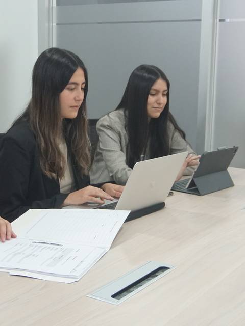 Tres mujeres trabajando juntas en una mesa de reuniones en un ambiente profesional.