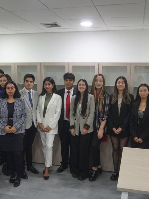 Grupo de personas posando juntas en una sala de trabajo.