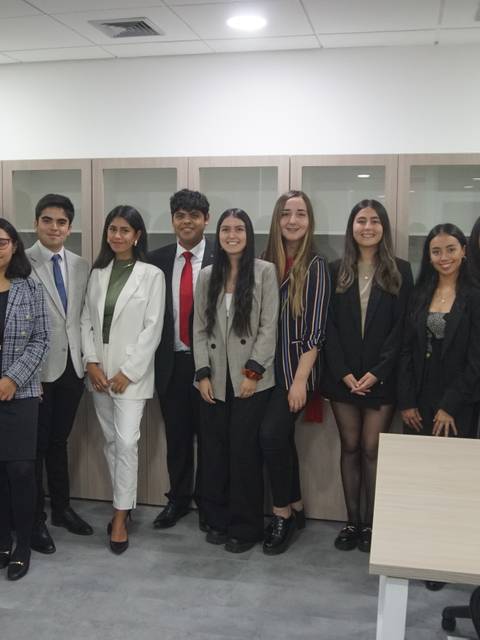 Un grupo de personas vestidas de manera formal posando en un entorno de oficina.