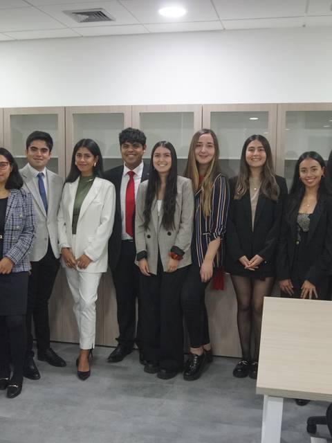 Un grupo de estudiantes y profesionales posan para una foto en un entorno de oficina moderno.