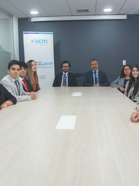 Un grupo de personas vestidas de forma profesional se reúne alrededor de una mesa en una sala de conferencias.