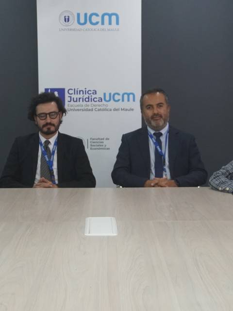 Un grupo de estudiantes y un profesor posan juntos en una sala de reuniones de una clínica jurídica.